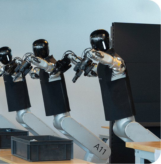Humanoid robots working together at a row of workstations